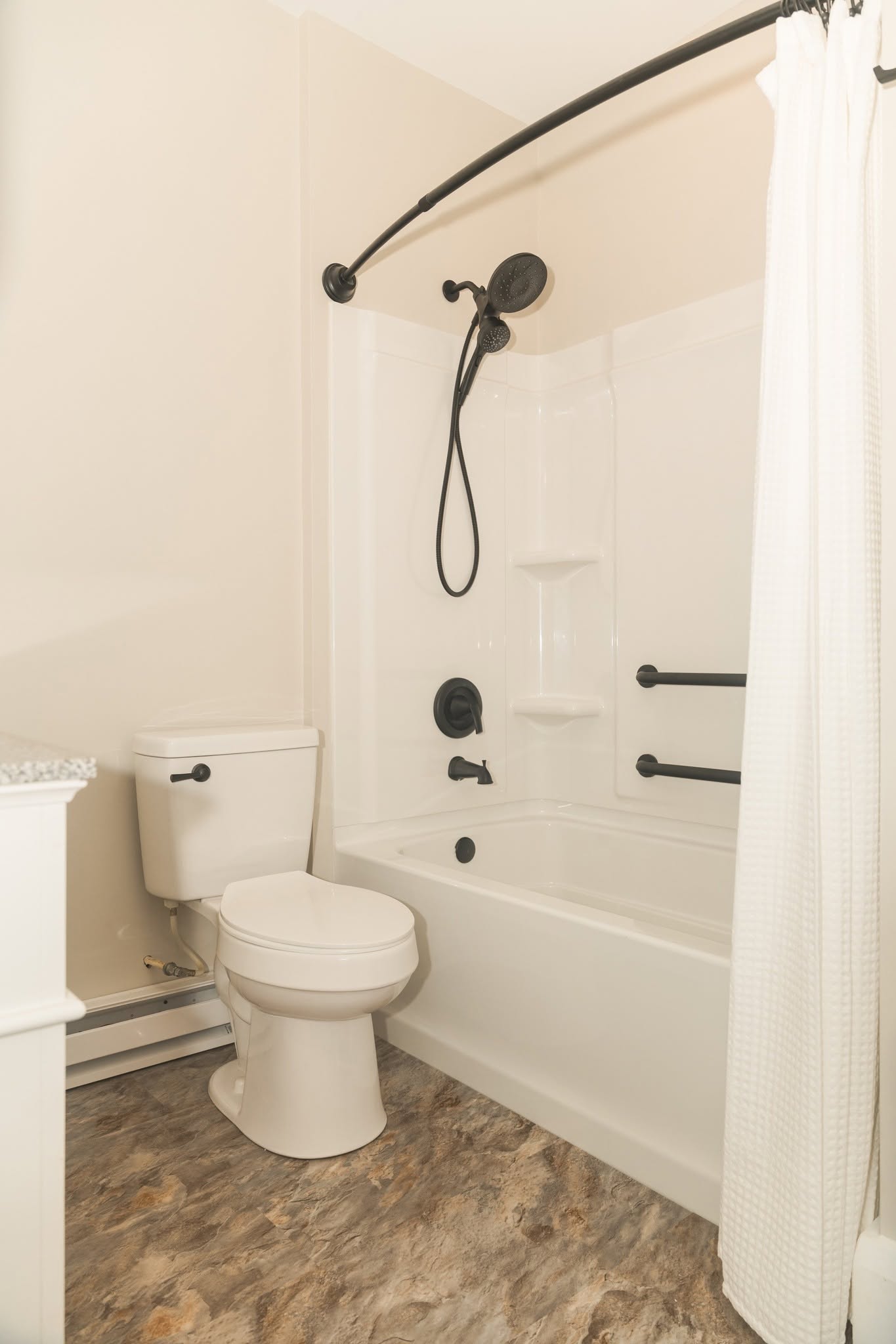 A remodeled bathroom with a white tub and shower and matte black fixtures