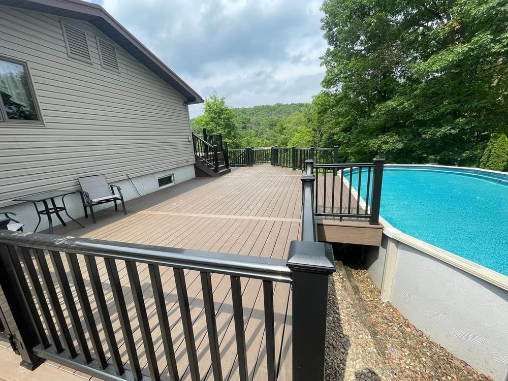 A composite deck with black railings overlooking a pool